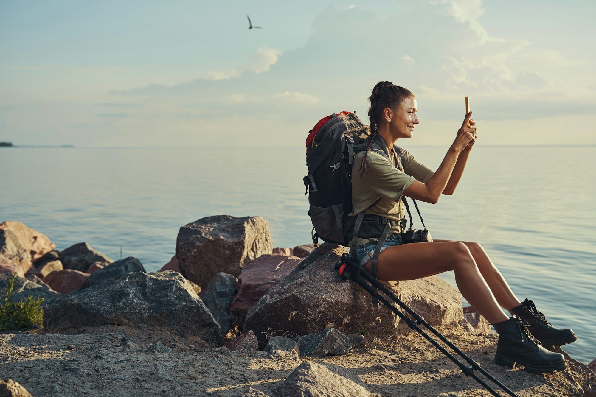 female-traveller-on-rock-taking-picture-of-sunset-e1705950714184.jpg